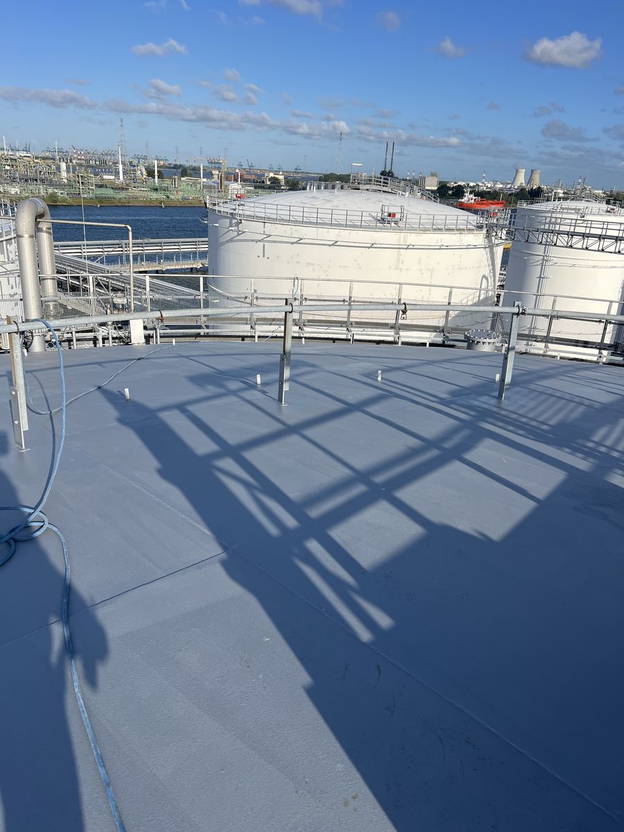 Vers gecoat tankdak in de haven: industriële atmosfeer, zeelucht en chemie in één omgeving